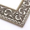 A large, reverse curve profile frame with an intricate leaf design bordered by a geometric outer edge and beaded inner lip.  A matte grey base, with silver foil patina along the topmost points of the design.  The beading is gold foil. Strong, solid wood construction.

2.75 " width: ideal for large and extra large (oversize) images.